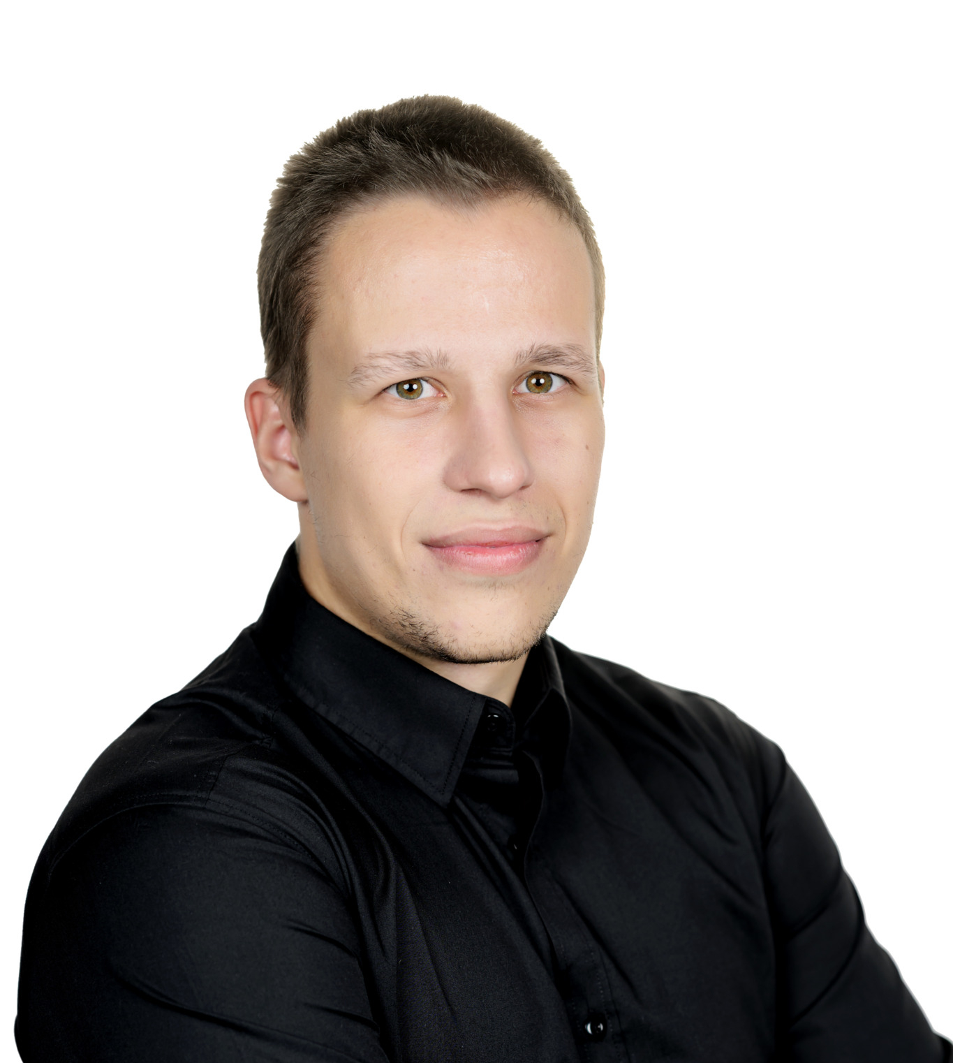 Portrait of a man in a black shirt with arms crossed, smiling slightly, against a white background.