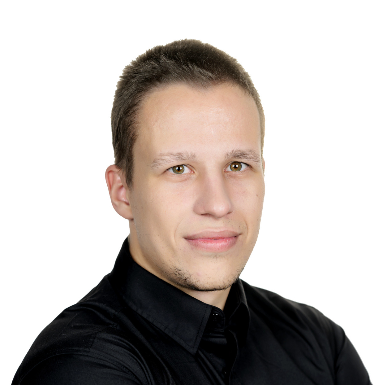 Portrait of a man in a black shirt with arms crossed, smiling slightly, against a white background.