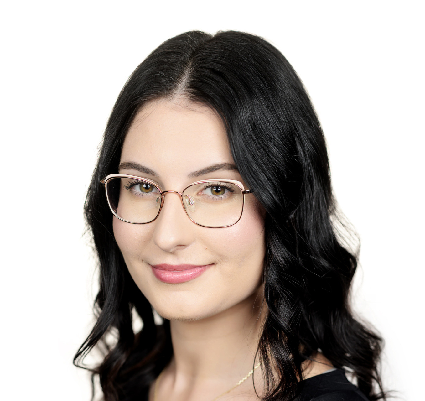 Portrait of a woman with dark hair and gold-rimmed glasses, wearing a black top and a small cross necklace, smiling subtly.