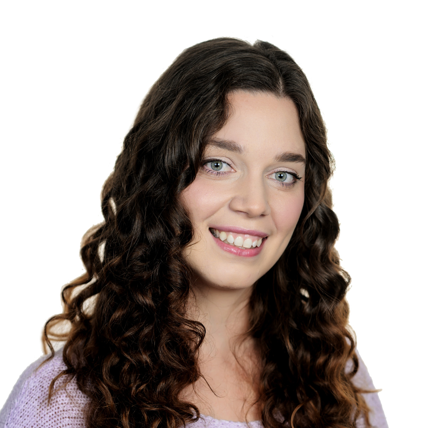 Smiling young woman with long, dark curly hair wearing a lavender knit sweater against a white background.